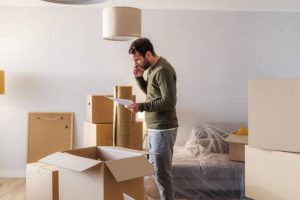 Mid adult man holding a lease agreement and talking on the phone. He is worried and he is moving out of the home.