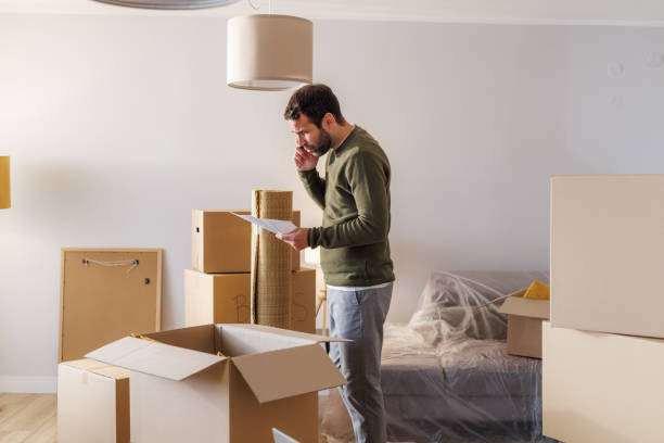 Mid adult man holding a lease agreement and talking on the phone. He is worried and he is moving out of the home.